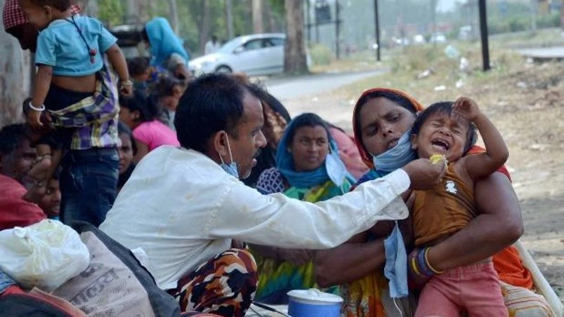 lockdown, coronavirus, Migrant workers A migrant feeds his child before boarding a bus for Ludhiana to travel to their native places, during the ongoing COVID-19 lockdown, in Amritsar