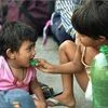 A migrant child feeds water to a toddler while waiting with their family to board a train at Central Railway station, during the ongoing nationwide COVID-19 lockdown, in Chennai