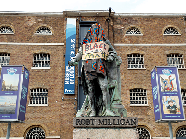 On voit la statue de Robert Milligan couverte d'une couverture et d'une affiche devant le Museum of London Docklands Robert Milligan