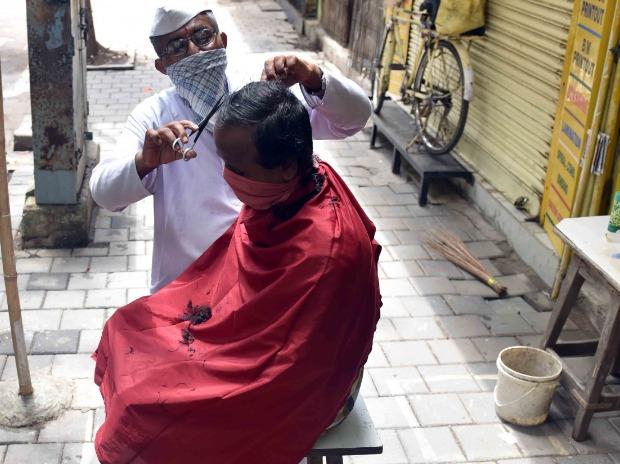 Barber shops and salons reopen in Mumbai: Nathu Bhawar attends to a customer at Fort in Mumbai Barber shops and salons reopen in Mumbai: Nathu Bhawar attends to a customer at Fort in Mumbai