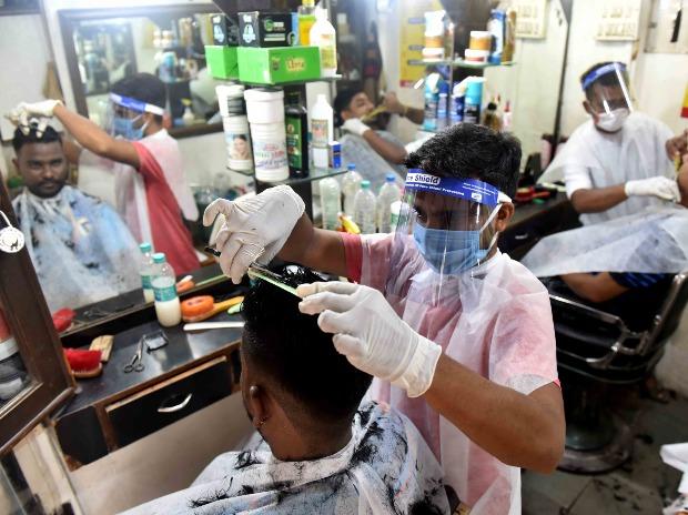 A hair-stylist wearing protective suit face shields attends to a customer at a Mumbai Hair Dressers at Fort in Mumbai A hair-stylist wearing protective suit face shields attends to a customer at a Mumbai Hair Dressers at Fort in Mumbai