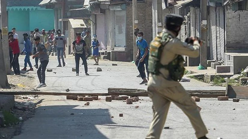 stone pelting, Indian Army, Srinagar, Jammu, Kashmir, Batamaloo A security official tries to stop protesters from throwing stones on them after an encounter with militants, at Batamaloo in Srinagar. Photo: PTI