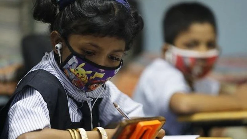digital learning, education, school, students, edutech, A student watches an online lecture on a mobile phone inside a digital mobile education library in Mumbai. Photo: Reuters