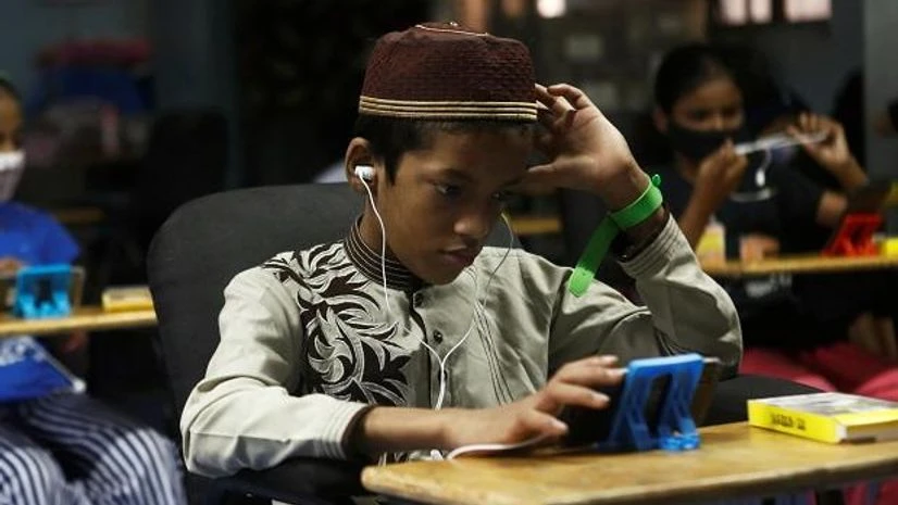 digital learning, education, school, students, edutech, A student watches an online lecture on a mobile phone inside a digital mobile education library in Mumbai. Photo: Reuters
