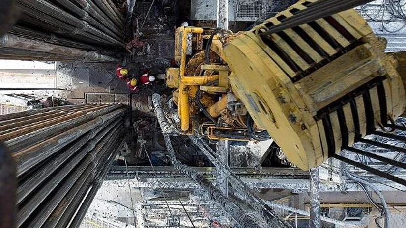 Oil, oil rig Oil workers operate drill sections while working on the drilling floor beneath the travelling block in Russia. Photo: Bloomberg
