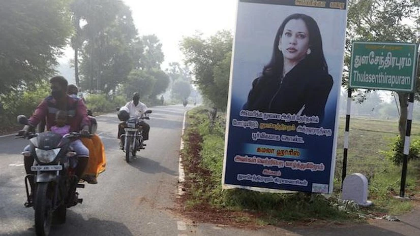 Kamala Harris, US Elections People ride past a billboard featuring U.S. democratic vice presidential candidate Sen. Kamala Harris at a crossing in Thulasendrapuram village, south of Chennai, Tamil Nadu | (AP Photo/Aijaz Rahi)