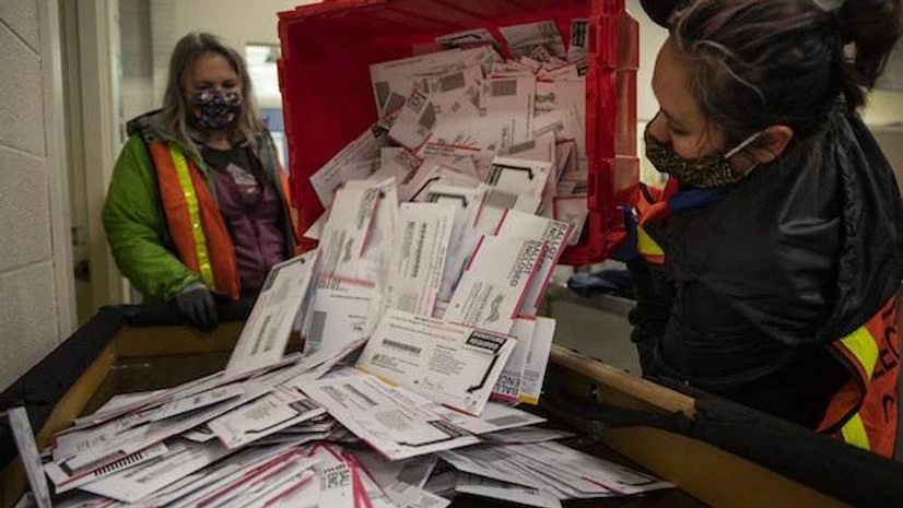 Biden edges ahead of Trump; chances of win widen as more votes come in Election worker Kristen Mun from Portland empties ballots from a ballot box at the Multnomah County Elections Division, Tuesday, Nov. 3, in Portland, Ore (AP Photo/Paula Bronstein)