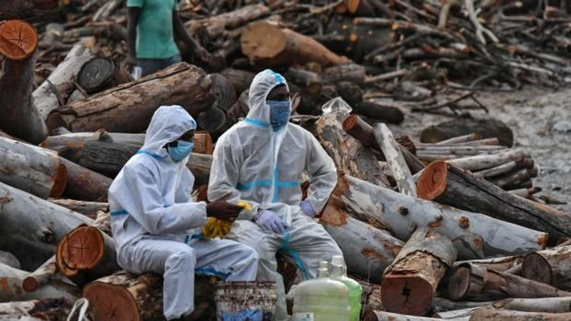 covid funeral Volunteers take a break during the cremation of people who died due to the coronavirus disease, at a crematorium ground in Giddenahalli village on the outskirts of Bengaluru (Photo: Reuters)