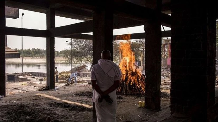 Coronavirus, funeral A relative observes the burning pyre of a Covid-19 fatality at a crematorium in Agra. Photo: Bloomberg