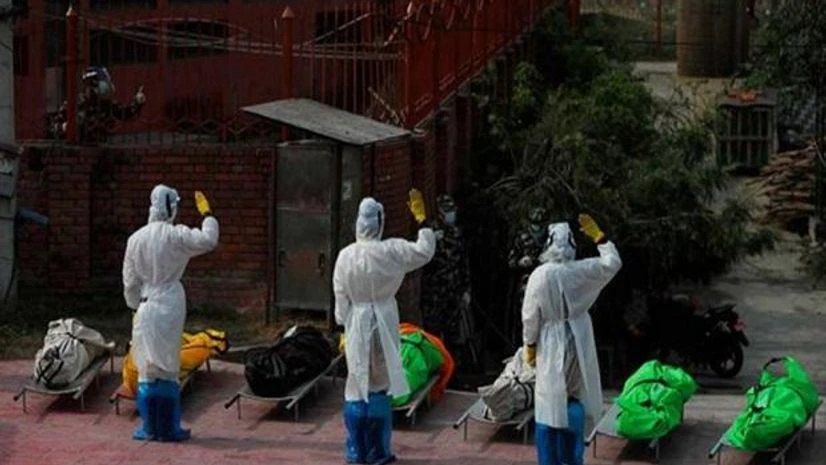 Nepal covid deaths, Covid-19 Nepalese army personnel in PPE suits salute to pay tributes to the COVID-19 victims before cremating their bodies near Pashupatinath temple in Kathmandu, Nepal. (Photo: AP/PTI)