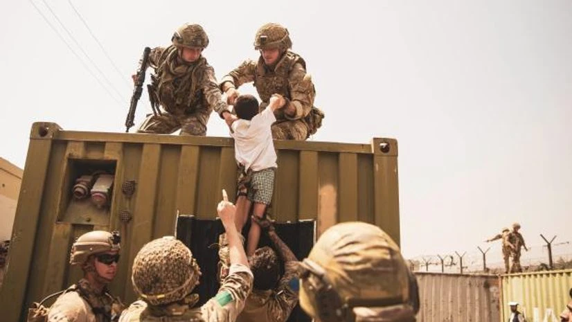 afghanistan In this image provided by the US Marine Corps, British and Turkish coalition forces, along with US Marines, assist a child during an evacuation at Hamid Karzai International Airport in Kabul