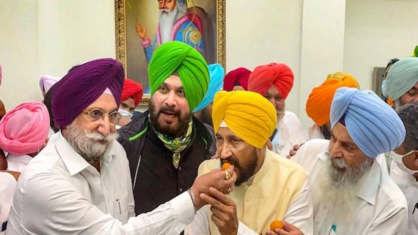New Punjab Chief Minister Charanjit Singh Channi being offered sweets by new State Deputy Chief Minister Sukhjinder Singh Randhawa, after his oath taking ceremony at Raj Bhawan in Chandigarh (Photo: PTI) New Punjab Chief Minister Charanjit Singh Channi being offered sweets by new State Deputy Chief Minister Sukhjinder Singh Randhawa, after his oath taking ceremony at Raj Bhawan in Chandigarh (Photo: PTI)