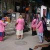 Workers with Accredited Social Health Activist (ASHA) from India's National Rural Health Mission wearing pink robes and protective masks, talk to a resident, left, as they conduct a door-to-door survey on the coronavirus in Delhi on July 2, 2020.
