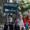 People sit next to a Covid test sign outside the School of Nursing in Jinnah Postgraduate Medical Centre (JPMC), in Karachi (File photo: Reuters)