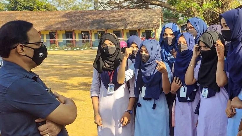 karnataka hijab row Kundapura: A faculty member talks with the students wearing hijab, after the school authorities denied them entry for wearing hijab in Kundapura of Udupi district, Saturday, Feb 5, 2022. (PTI Photo)