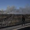 A pedestrian looks at a cloud of smoke rising after an explosion in Lviv, Western Ukraine, on March 18, 2022. The mayor of Lviv says missiles struck near the city's airport early Friday. (AP Photo/Bernat Armangue)