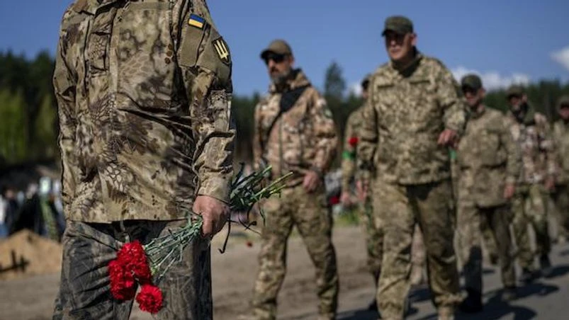 Ukraine, Ukraine soldiers Irpin Territorial Defence and Ukrainian Army soldiers hold flowers to be placed on the graves of comrades fallen during the Russian occupation, at the cemetery of Irpin, on the outskirts of Kyiv, on Sunday, May 1, 2022. (AP Photo/Emilio Morenatti)