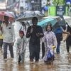 School students with their guardians wade through a flooded street following heavy monsoon rains, in Mumbai (Photo: PTI)