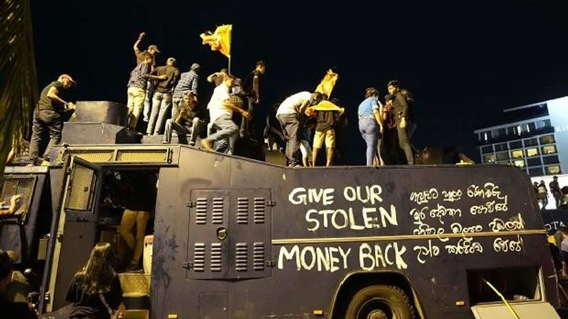 Protesters stand on a vandalised police water canon truck and shout slogans at the entrance to president's official residence in Colombo (Photo: AP/PTI) Protesters stand on a vandalised police water canon truck and shout slogans at the entrance to president's official residence in Colombo (Photo: AP/PTI)