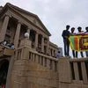 People stand holding a national flag at the President Gotabaya Rajapaksa's office on the second day after it was stormed in Colombo, Sri Lanka (Photo: AP/PTI)