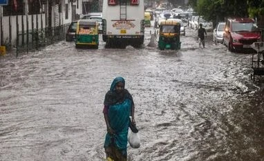 Traffic snarls, waterlogging mar Wednesday rain fun for Delhi residents A woman wades through a waterlogged road following incessant monsoon rains, in New Delhi (Photo: PTI)