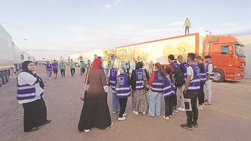 Volunteers wait next to a convoy of trucks carrying aid from Egyptian NGOs for Palestinians at the Rafah crossing photo: reuters Volunteers wait next to a convoy of trucks carrying aid from Egyptian NGOs for Palestinians at the Rafah crossing photo: reuters