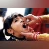 A young Indian girl receiving a dose of oral polio vaccine by a trained healthcare worker
