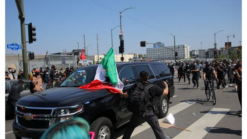 LA protest, LA protesters, Los Angeles A demonstrator holds a Mexican flag while aiming a fist towards a law enforcement vehicle, during a protest against federal immigration sweeps in downtown Los Angeles, California, U.S. June 8, 2025