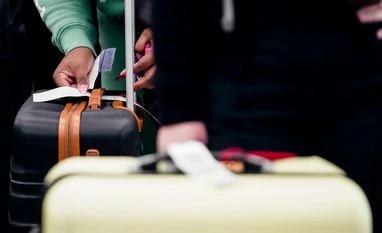 A traveler puts a tag on their luggage. VIP Industries share price today, November 17, 2025