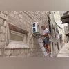 An electrician installs an air conditioning unit in the Old Town district of Kotor, Montenegro