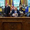 Trump speaks as he sits next to a sign that reads "Trump Gold Card is here", with U.S. Secretary of Commerce Howard Lutnick standing by his side| REUTERS