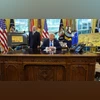Trump speaks as he sits next to a sign that reads "Trump Gold Card is here", with U.S. Secretary of Commerce Howard Lutnick standing by his side| REUTERS