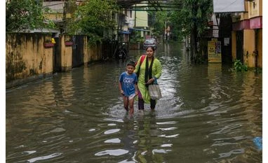 Heavy rainfall, Kolkata rainfall, waterlogging Kolkata: A woman takes a child through a waterlogged road following rain, in Kolkata, Tuesday, Sept. 23, 2025