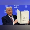 US President Donald Trump holds a signed Charter of the Board of Peace, as he takes part in a charter announcement for his Board of Peace initiative aimed at resolving global conflicts, alongside the 56th annual World Economic Forum (WEF), in Davos.
