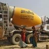 Workers walk in front of an UltraTech concrete mixture truck at the construction site of a commercial complex on the outskirts of Ahmedabad