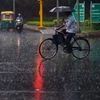 A cyclist crosses a road during monsoon rainfall at Zakir Hussain Marg, in New Delhi