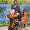 People take a selfie with the poster of Tamil actor Rajinikanth's movie '2.0', in Mumbai
