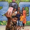 People take a selfie with the poster of Tamil actor Rajinikanth's movie '2.0', in Mumbai