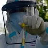 A doctor wearing protective gear holds a sample test tube at COVID-19 test centre during a nationwide lockdown as a preventive measure against the coronavirus, in Srinagar. Photo: ANI