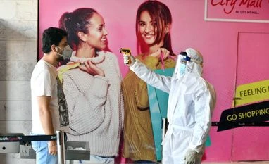 A security guard wears protective gear suit as he uses thermal screening on people at a shopping mall after the authorities permitted the opening of shopping marts after two months lockdown at Gour city mall in Greater Noida on Tuesday. A security guard wears protective gear suit as he uses thermal screening on people at a shopping mall after the authorities permitted the opening of shopping marts after two months lockdown at Gour city mall in Greater Noida on Tuesday.