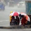 People hold umbrella as they protect themselves from heavy rainfall, in Mumbai on Sunday.