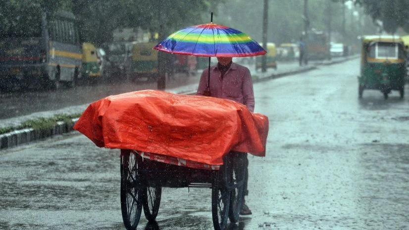 Delhi rain A vendor covers his cart as he hold umbrella to protect himself from heavy rainfall, in New Delhi on Wednesday.