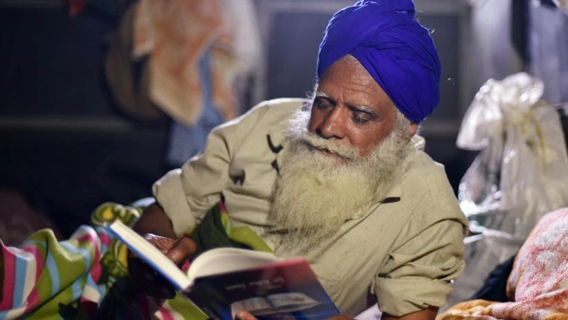 Farmer protest Farmer reads a book during their protest against new farms law, at Singhu Border in New Delhi on Saturday.