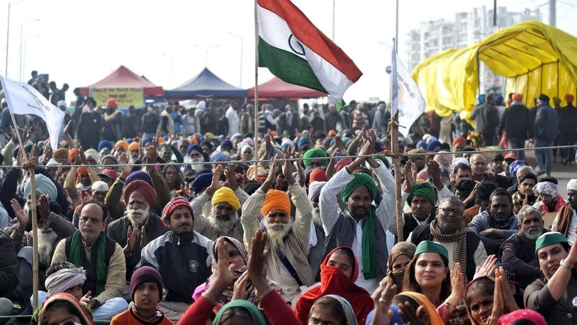 Farmers sitting as they host the national flag during an ongoing protest against the new warm laws, at the Ghazipur border in New Delhi on Saturday. Farmers sitting as they host the national flag during an ongoing protest against the new warm laws, at the Ghazipur border in New Delhi on Saturday.