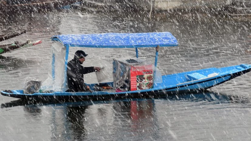 A boatman rides a shikara during fresh snowfall, in Srinagar shikara