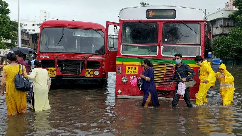 Mumbai rain People go past the stuck bus in the logged water as the city observes heavy rain, in Mumbai on Wednesday. IMD issues a red alert for Mumbai as the monsoon arrives.
