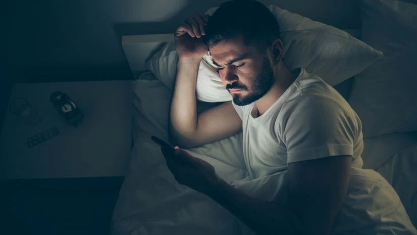 Bedrotting man scrolling on phone
